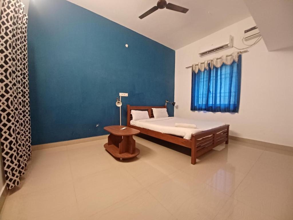a bedroom with a bed and a blue wall at ECO tree inn Villa in Kottakupam