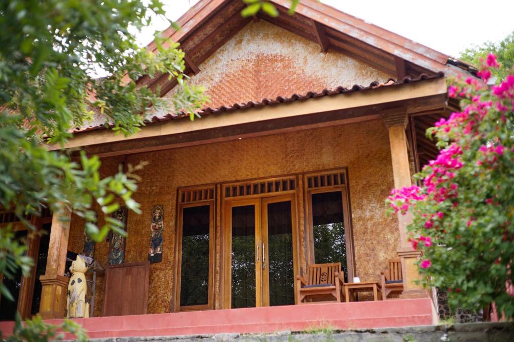 een huis met houten deuren en stoelen en bloemen bij Yut's Inn Flower Paradise Gili Gede in Gili Gede