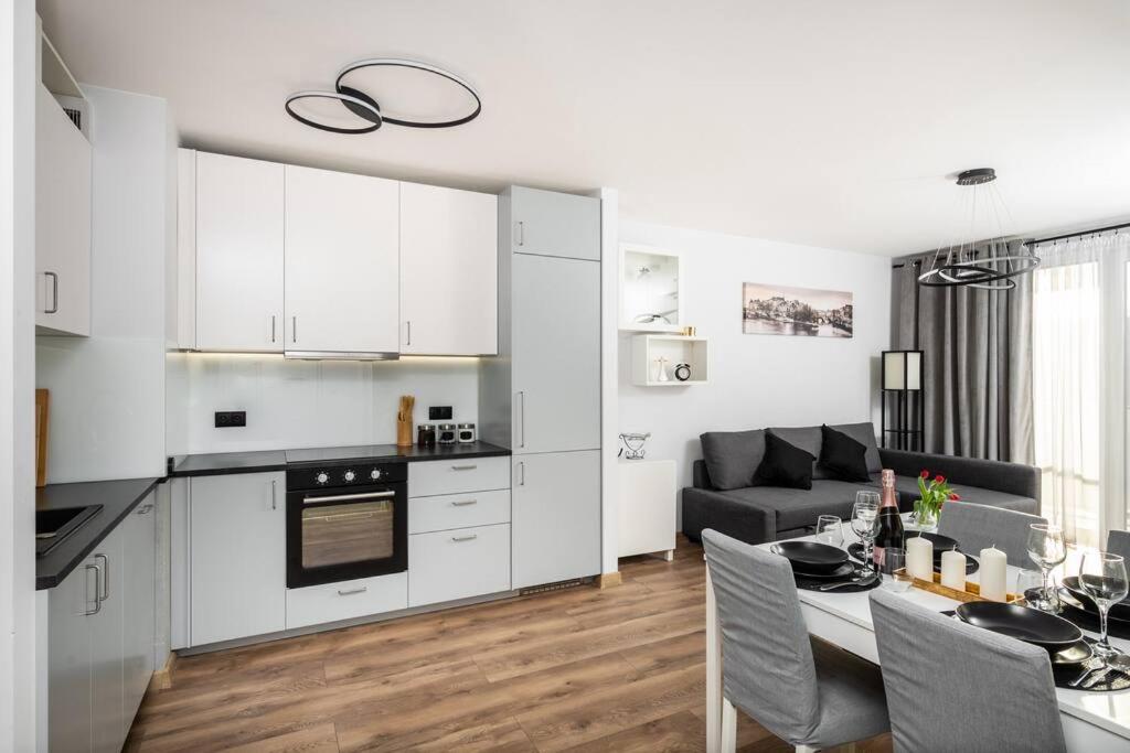 eine Küche und ein Wohnzimmer mit weißen Schränken und einem Tisch in der Unterkunft Capital Apartments in Krakau