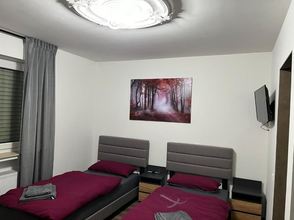 シュヴェービッシュ・ハルにあるHausOase Zimmervermietungのベッドルーム1室(ベッド2台付)が備わります。壁には絵画が飾られています。