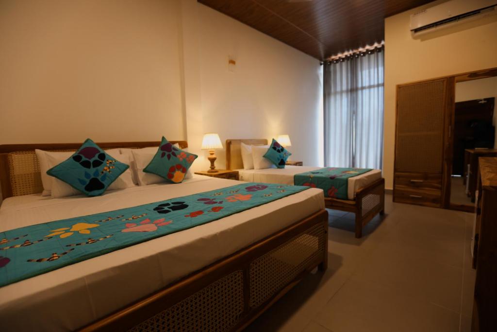 a hotel room with two beds and a window at Coop Safari Hotel in Tissamaharama