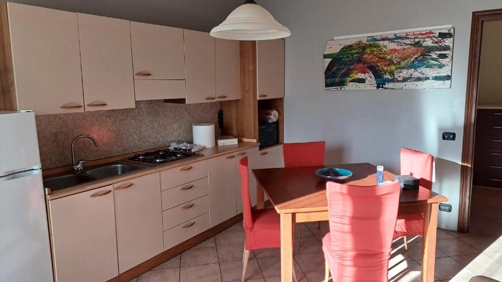 eine Küche mit einem Tisch, einer Spüle und einem Kühlschrank in der Unterkunft Casa Olimpia in Priocca