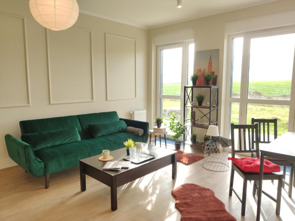 a living room with a green couch and a table at Apartament Prezydencki na Letniej 71m2 z Ogrodem i Widokiem na Góry Kłodzko - Przyjaciół Ziemi Kłodzkiej in Kłodzko