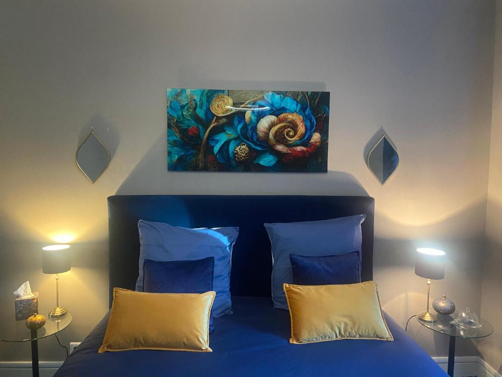 um quarto com uma cama azul com um quadro na parede em Le moulin de la Vernoelle em Prémilhat