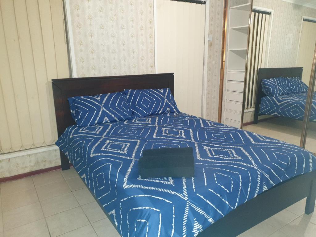 a bedroom with a bed with a blue and white comforter at Private room with shared facilities W in Werribee