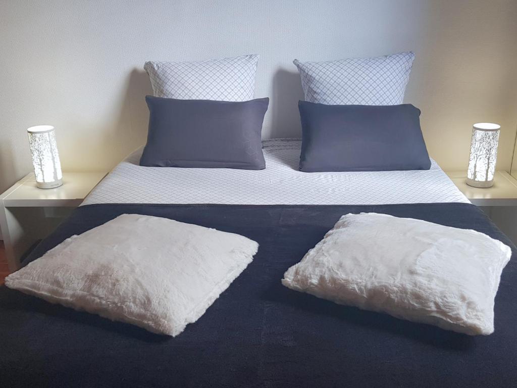 a bed with white sheets and blue pillows at Vue sur la Bastille - Appt Calme et Cosy-Netflix-Fibre in Grenoble