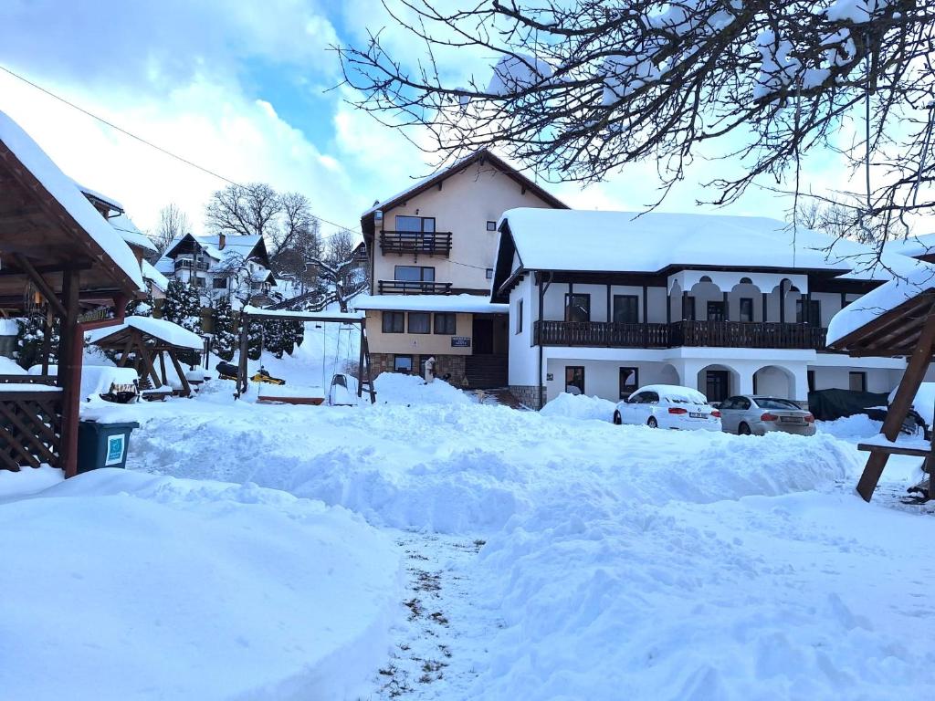 un patio cubierto de nieve con casas y coches en Pensiunea Sarah Bran, en Bran