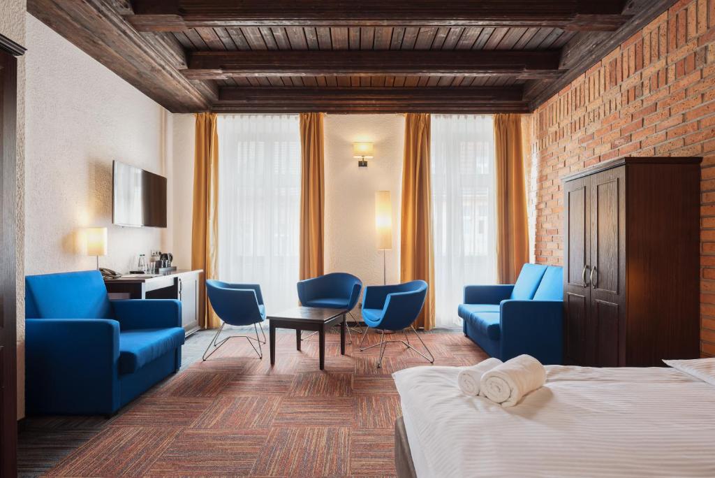 a hotel room with blue chairs and a bed at Palazzo Rosso Old Town in Poznań