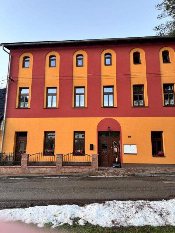 a red and orange building on the side of a street at Apartmán U Splavu in Teplice nad Metují