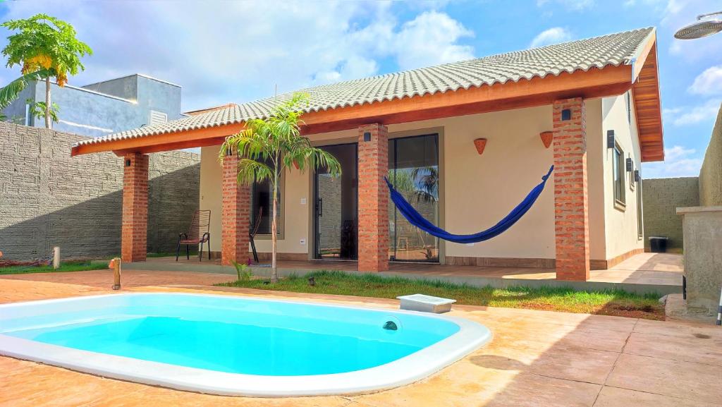 a pool in front of a house with a hammock at Aconchego próximo ao Thermas in Olímpia