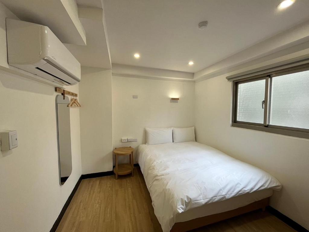 um pequeno quarto com uma cama branca e uma janela em 宏洲旅社HZ Hotel em Taipei