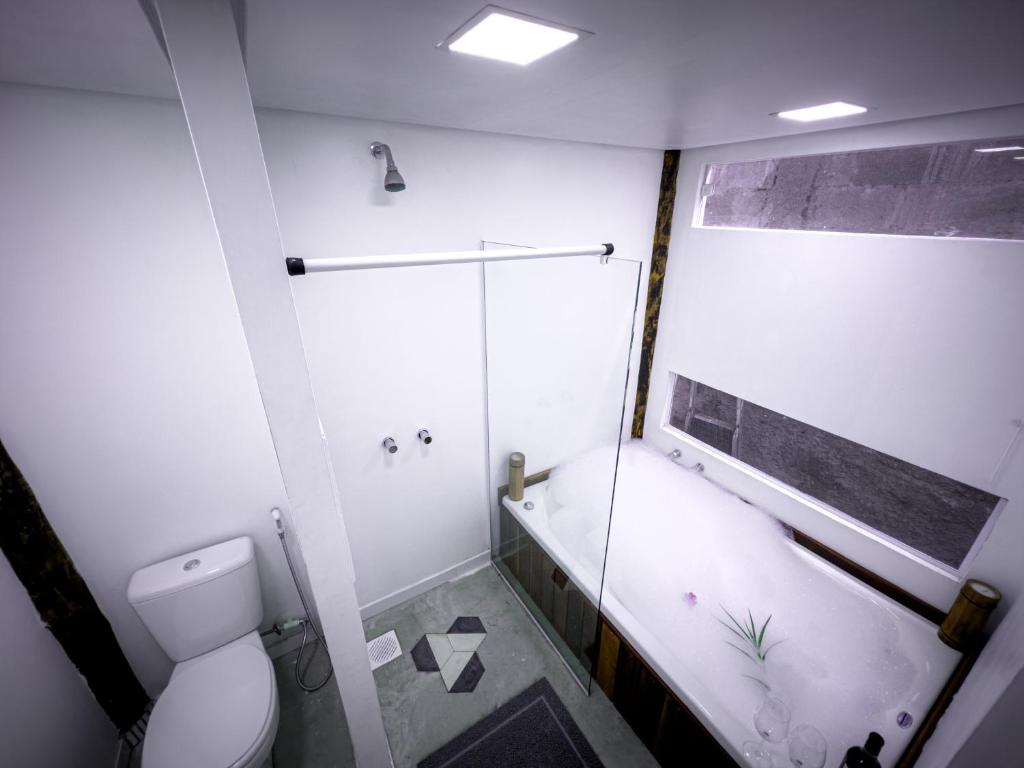 a white bathroom with a shower and a toilet at Flats do Pe na Areia in Abraão