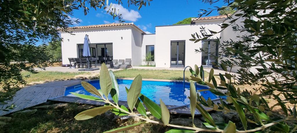 une villa avec une piscine en face d'une maison dans l'établissement Villa neuve de standing au calme, à Sommières