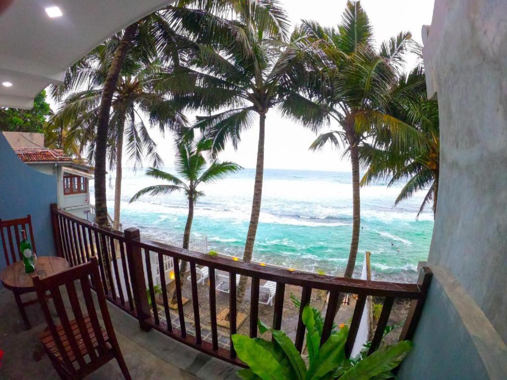 a balcony with a view of the ocean and palm trees at Asa Bay Beach Resort in Talpe