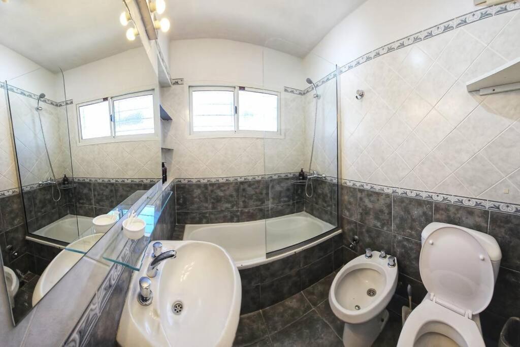 a bathroom with a sink and a toilet and a tub at OlaLasGrutas Casa 4ta Bajada in Las Grutas