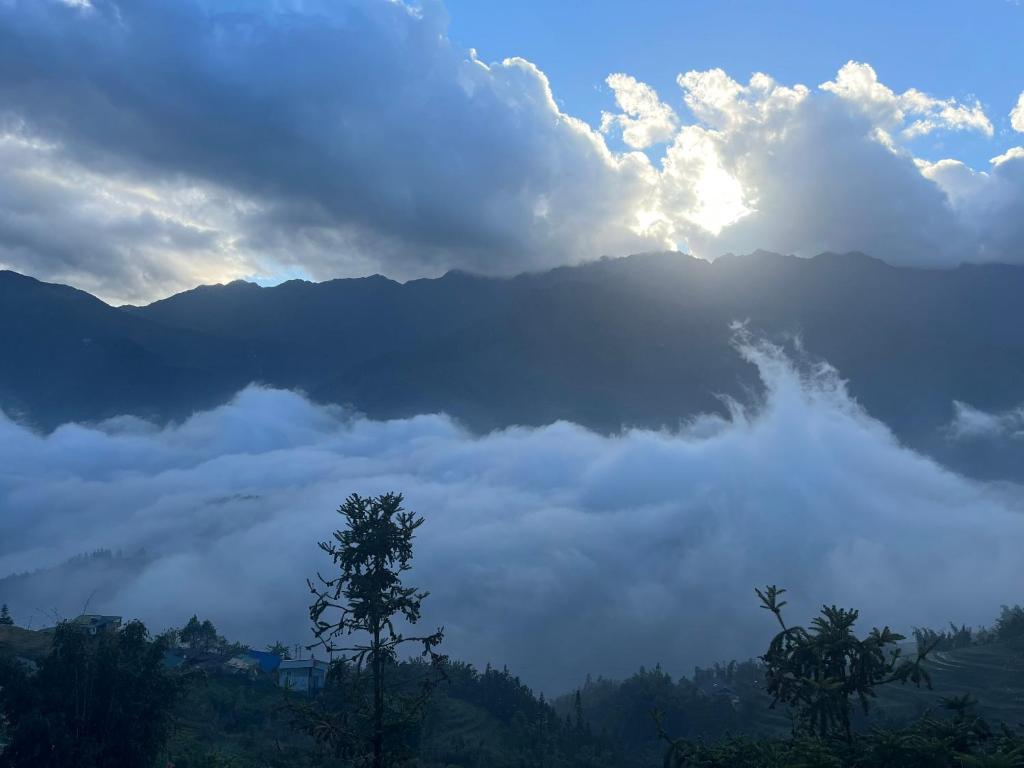 una vista di una montagna nebbiosa con il sole che soffia tra le nuvole di Sapa Valley view hotel a Sa Pa