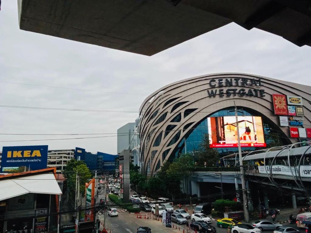 Near central westgate at bangyai 80 في Ban Bang Krabu: شارع المدينة مزدحم مع مبنى عليه لافتة