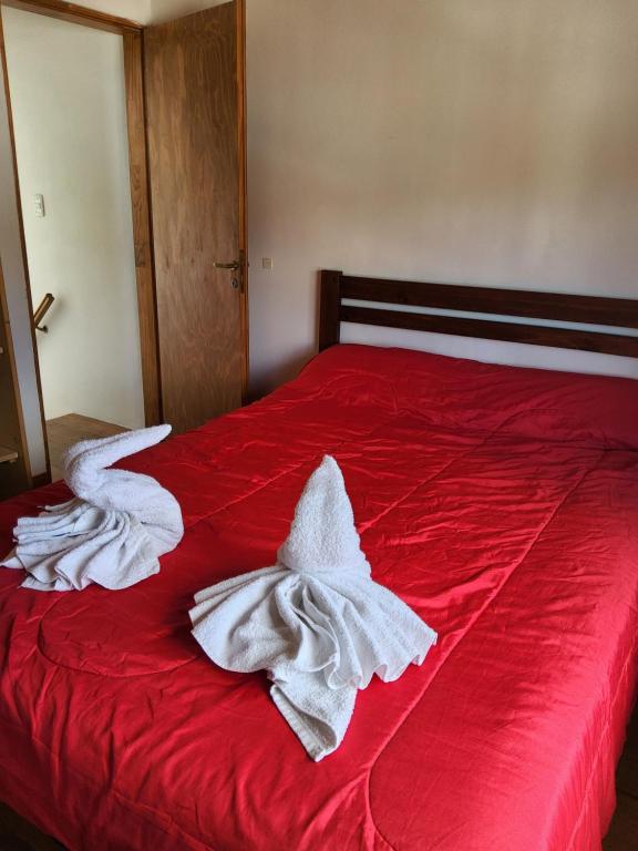 a red bed with white towels on it at La Bonaerense departamento centrico in Esquel