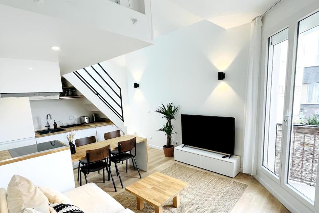 un salon avec un canapé, une télévision et une table dans l'établissement Duplex Loft industrial, Flea market St Ouen, Quiet, à Saint-Ouen