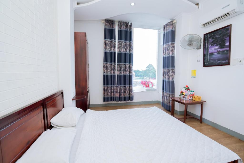 a bedroom with a large bed and a window at Triệu Vũ Hotel & Apartment in Buon Ma Thuot