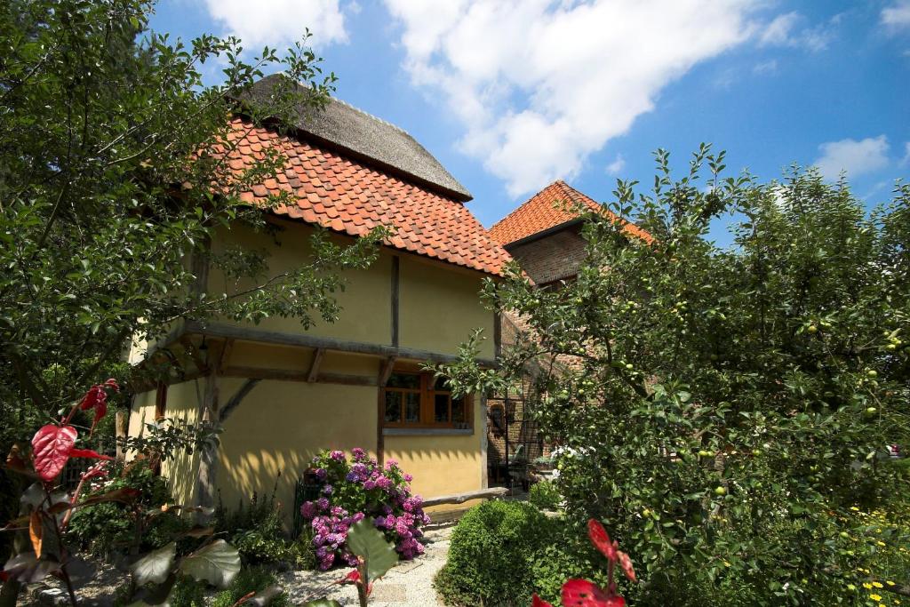 ein gelbes Haus mit rotem Dach und ein paar Blumen in der Unterkunft B&B Tspijker in Mol