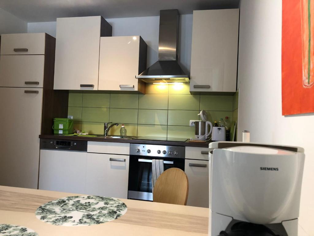eine Küche mit weißen Geräten und einem Holztisch in der Unterkunft Aparthotel Ochsenfurt mit Terrasse für aktive Reisende in Ochsenfurt
