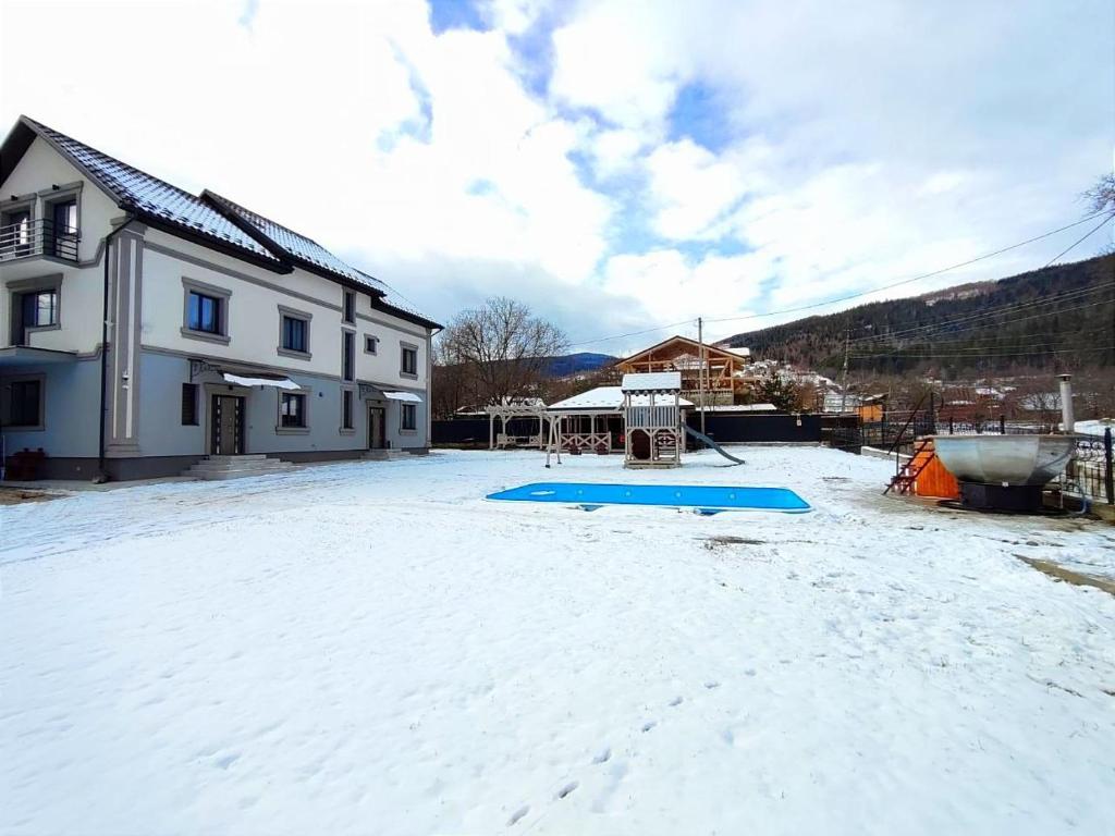 a snow covered yard in front of a house at Margo in Yaremche