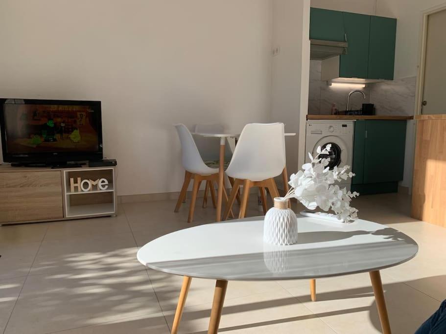 ein Wohnzimmer mit einem Tisch und einem TV in der Unterkunft Maisonnette dans belle résidence in Saint-Vallier-de-Thiey
