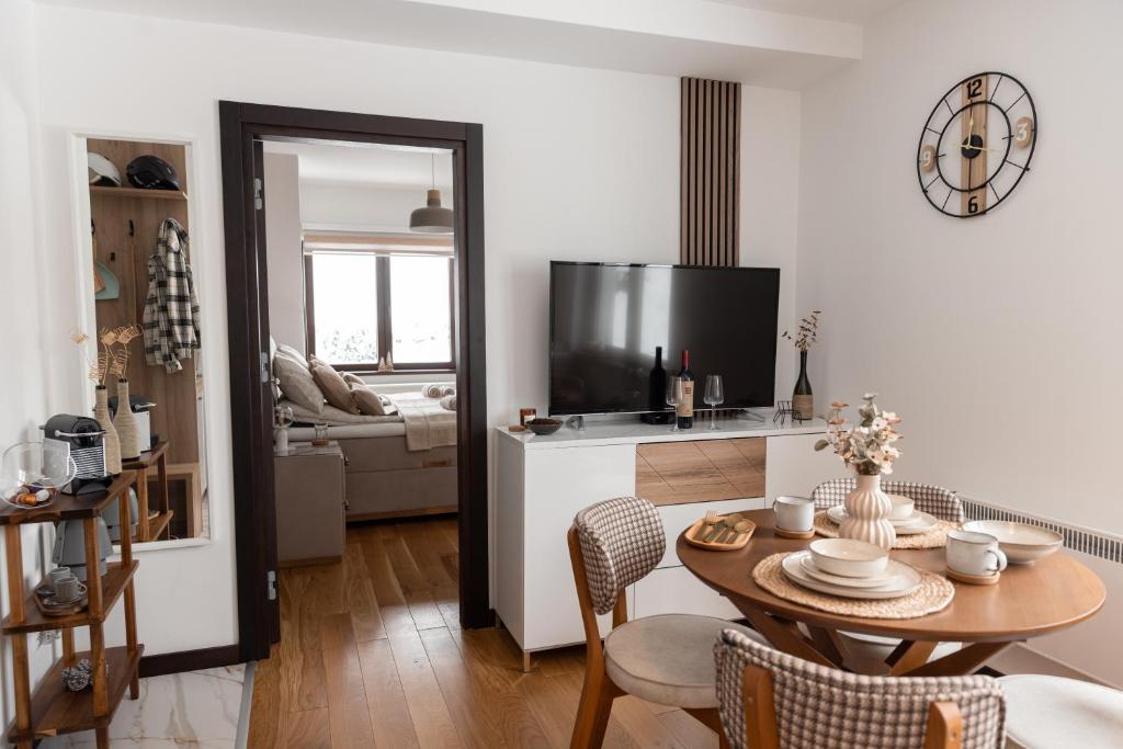 uma sala de estar com uma mesa e uma sala de estar com uma televisão em Glečer Kop, apartment A14 em Kopaonik