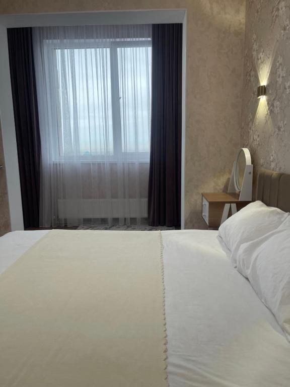 1 cama blanca grande en un dormitorio con ventana en Квартира посуточно Алматы en Almaty