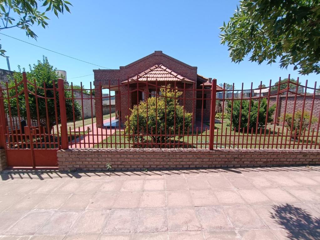 a red fence with a building behind it at Doña Ines in General Acha