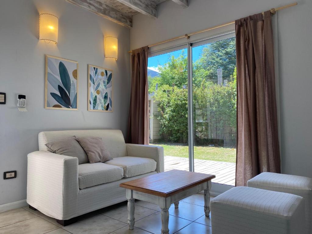 Una sala de estar con un sofá y una mesa y una ventana. en BOG Las Frutillas 1, en Villa La Angostura