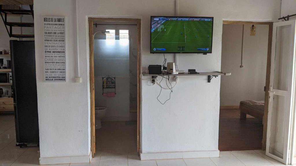 a living room with a tv on the wall and a room with at Villa Fahasoavana in Antananarivo