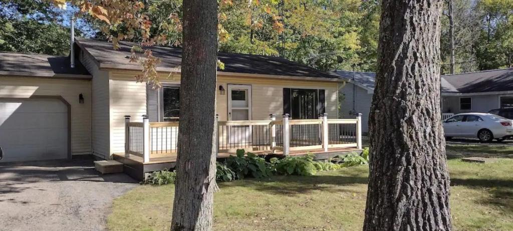une petite maison avec une terrasse couverte et un garage dans l'établissement Close to all the outdoor fun!, à Higgins Lake