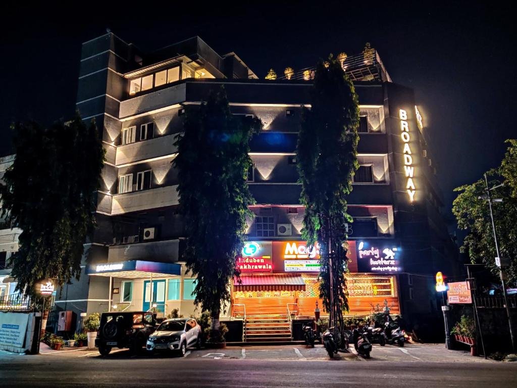 un edificio con árboles delante de él por la noche en Hotel Broadway Udaipur, en Udaipur