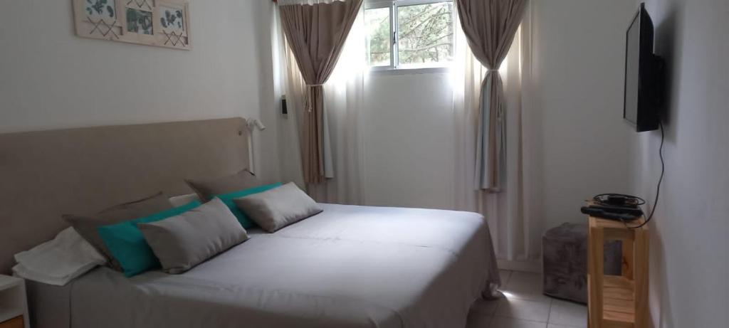 a white bed in a room with a window at Acacia in Pinamar