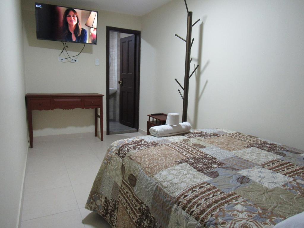 1 dormitorio con 1 cama y TV de pantalla plana en KORPAWASY, en Ipiales