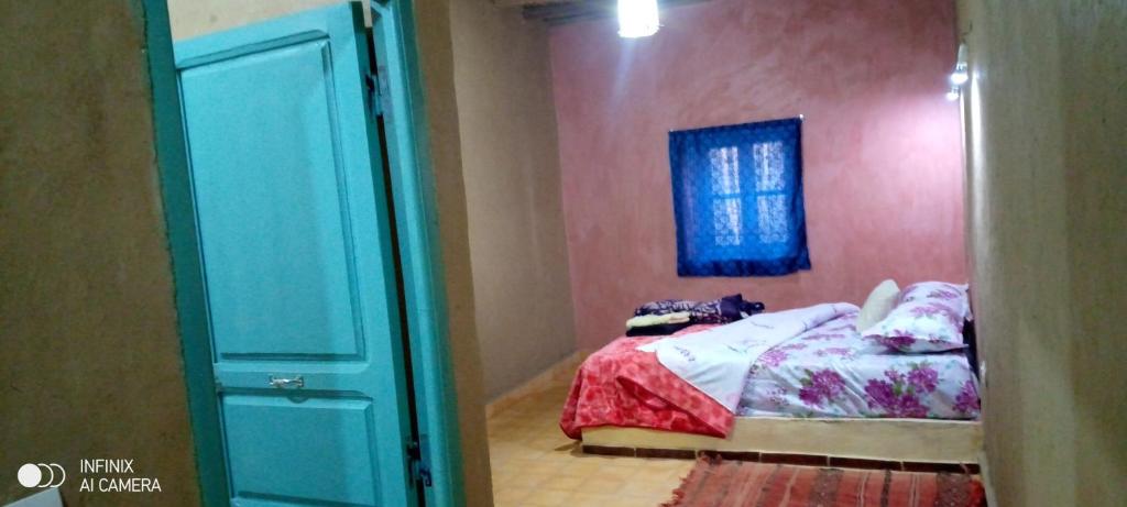 um quarto com uma cama, uma janela e uma porta em DAR AMMAR em Merzouga