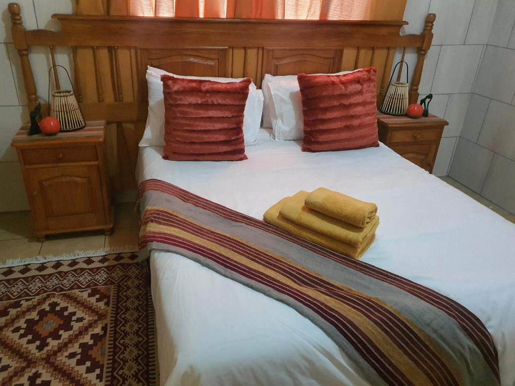 a bed with two pillows and two towels on it at Mpucuko Guest House in Mtubatuba