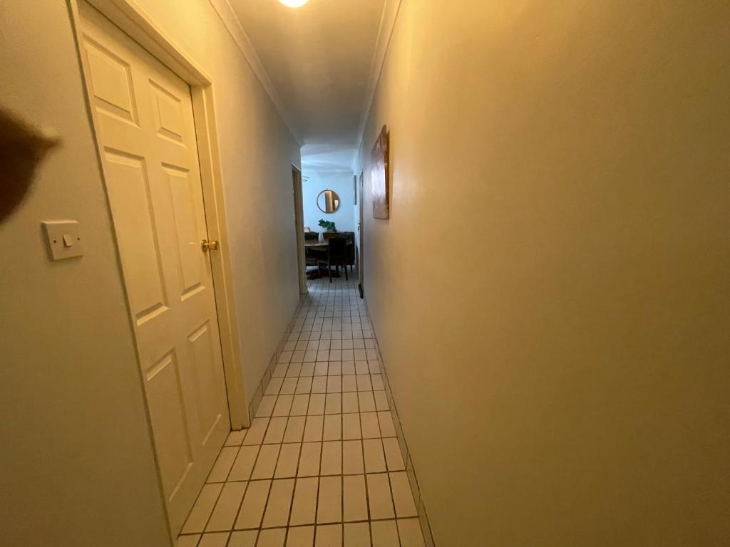 korytarz z białymi drzwiami i podłogą wyłożoną kafelkami w obiekcie Melrose place w mieście Francistown