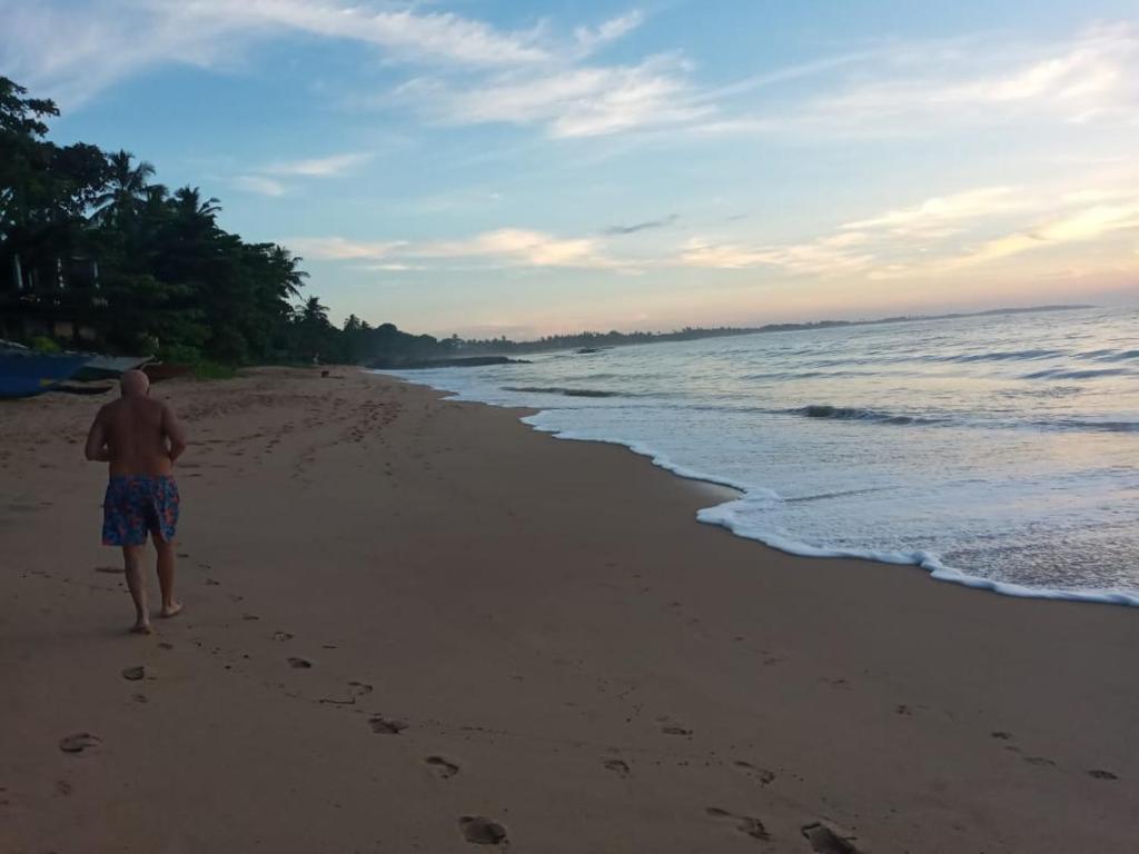 a man walking on a beach with footprints in the sand at Sasagara Beach Villa in Tangalle