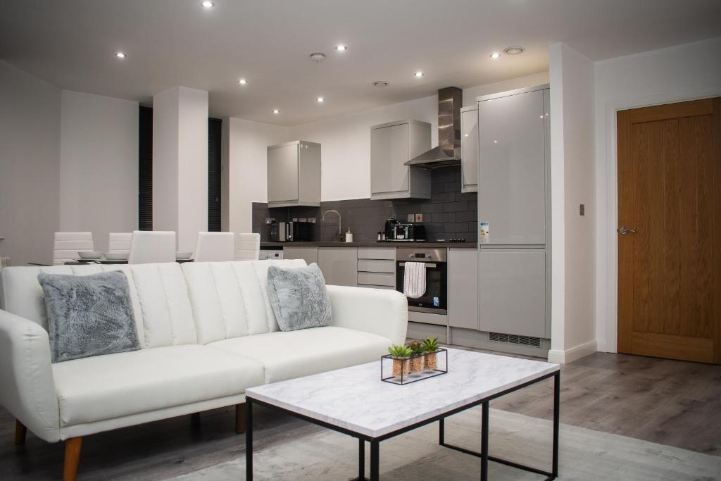 a living room with a white couch and a table at Exquisite 2-Bedroom City Centre Haven - Leicester's Premier Urban Retreat in Leicester