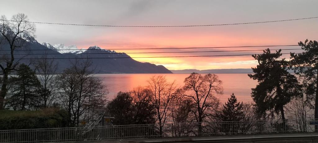 um pôr do sol sobre a água com uma montanha em Castle view em Veytaux