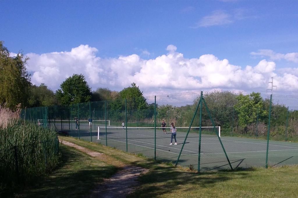 two people playing tennis on a tennis court at Résidence Goélia Le Cordouan in Soulac-sur-Mer