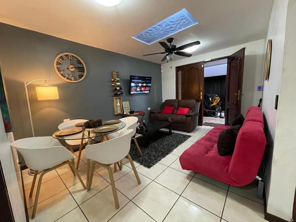 ein Wohnzimmer mit einem roten Sofa und einem Tisch in der Unterkunft Elegante Casa de 4 Habitaciones a Solo 15 Minutos del Corazón de la Ciudad in San José