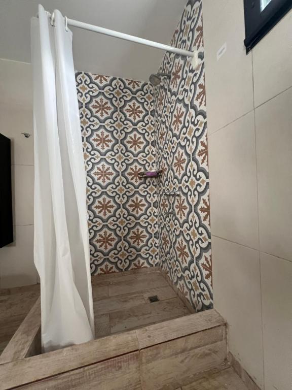 La salle de bains est pourvue d'un rideau de douche et d'un mur en carrelage. dans l'établissement El Eden2, à Playa Dorada