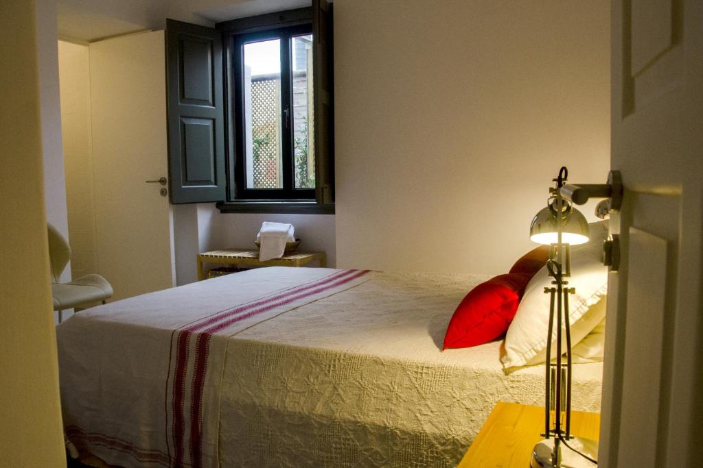 um quarto com uma cama com almofadas vermelhas e uma janela em Pensao Sisudo em Sintra