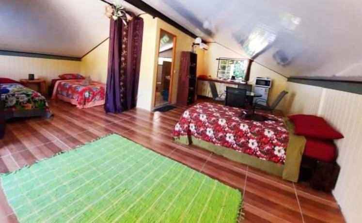 a bedroom with two beds and a green rug at Studio Rava 1 Room Fare Tepua Lodge in Uturoa