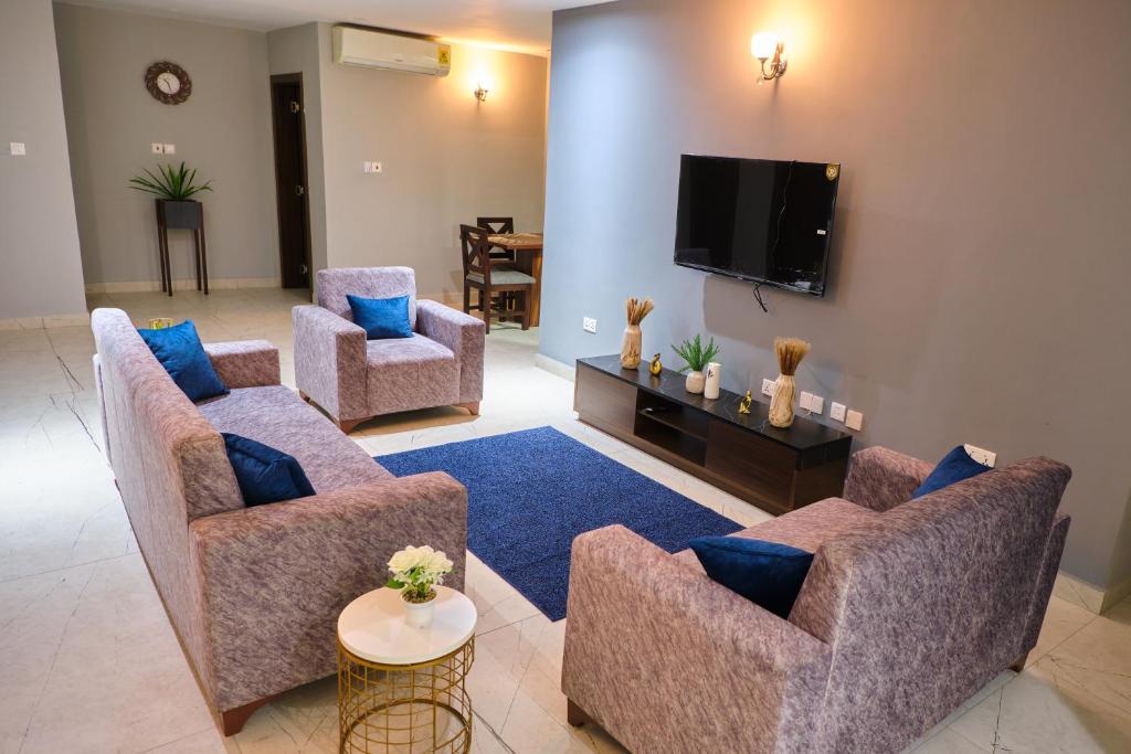 uma sala de estar com 2 sofás e uma televisão de ecrã plano em The Pearls - Penthouse em East Legon