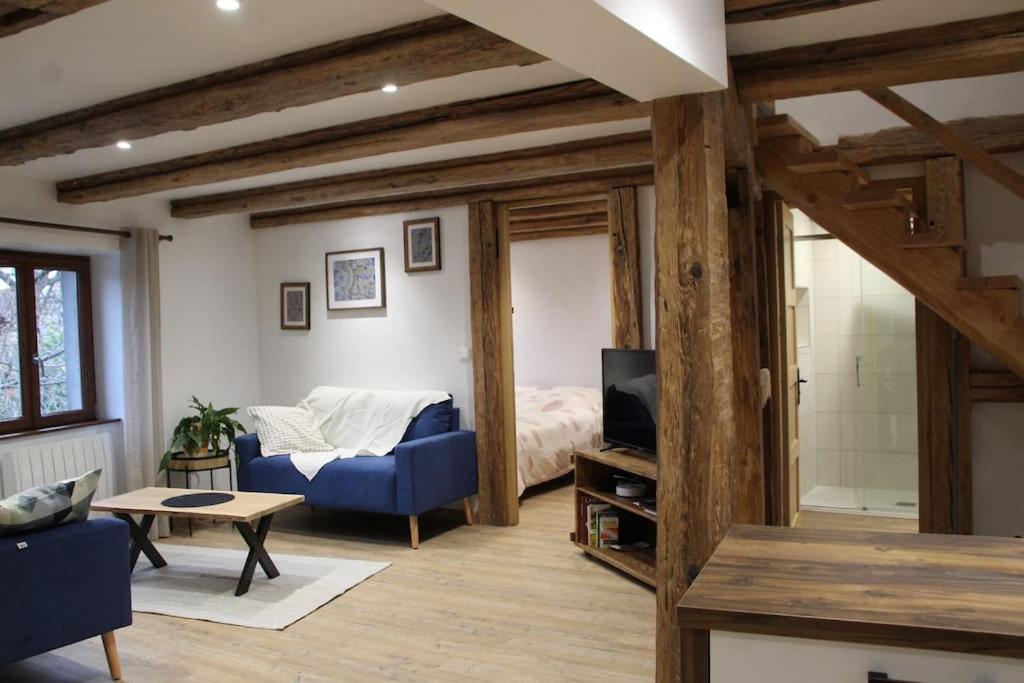 uma sala de estar com um sofá azul e uma cama em La p'tite maison em Orschwihr